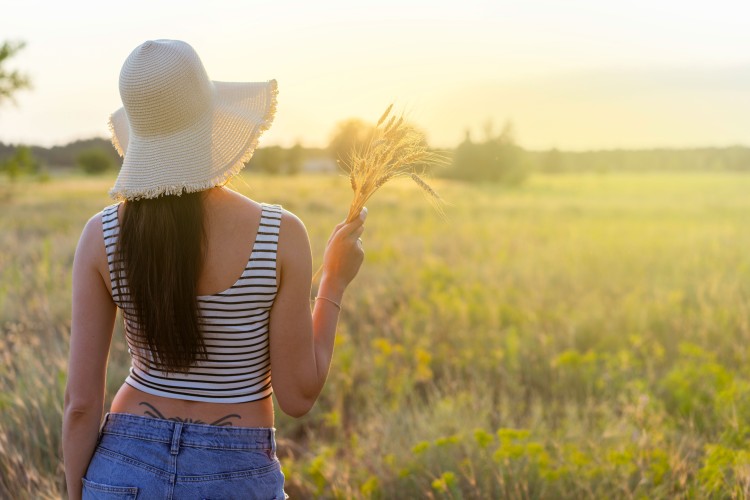brunette-woman-in-a-straw-hat-holds-ears-of-wheat-in-his-hand