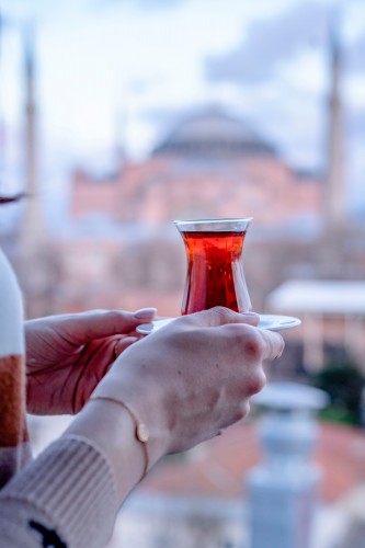 person-holding-turkish-tea-on-blurred-background
