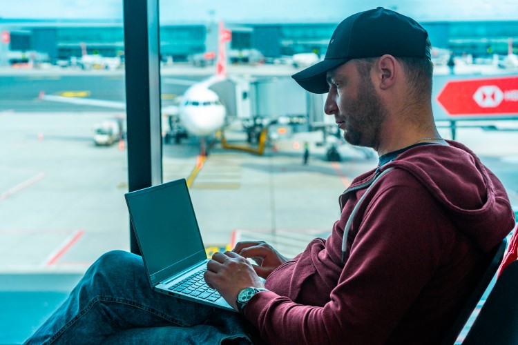 man-in-hat-working-with-laptop-in-airport