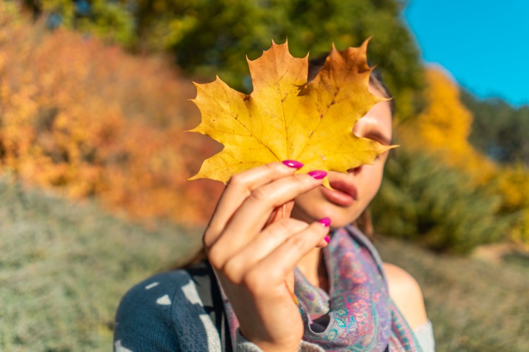 brunette-woman-in-a-sweater-with-a-yellow-leaf-in-hand