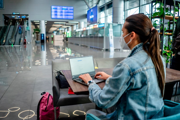 woman-in-mask-working-with-laptop-in-airport