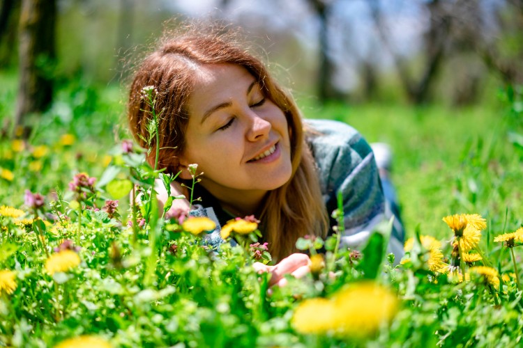 smiling-woman-lying-on-the-grass-with-flowers