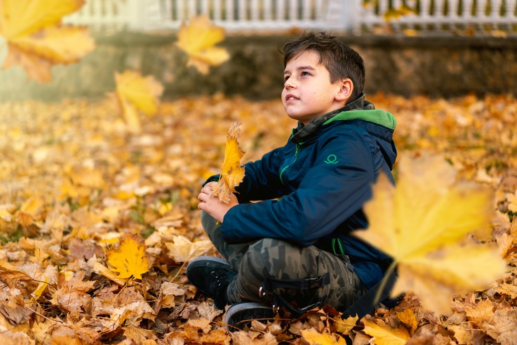 pensive-kid-sitting-on-the-autumn-leaves