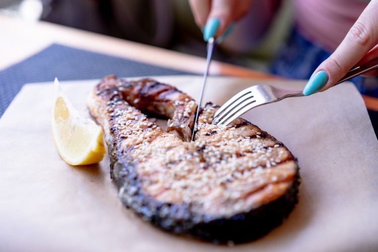 woman-eats-grilled-fish-steak-with-lemon