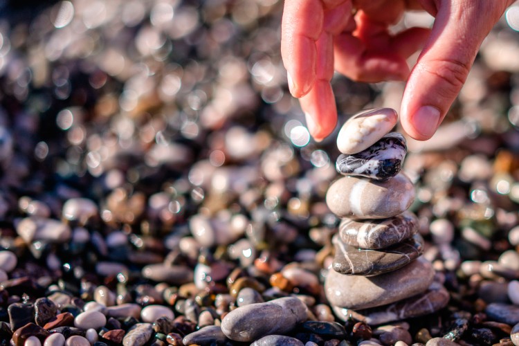 person-making-pebble-tower-at-the-beach