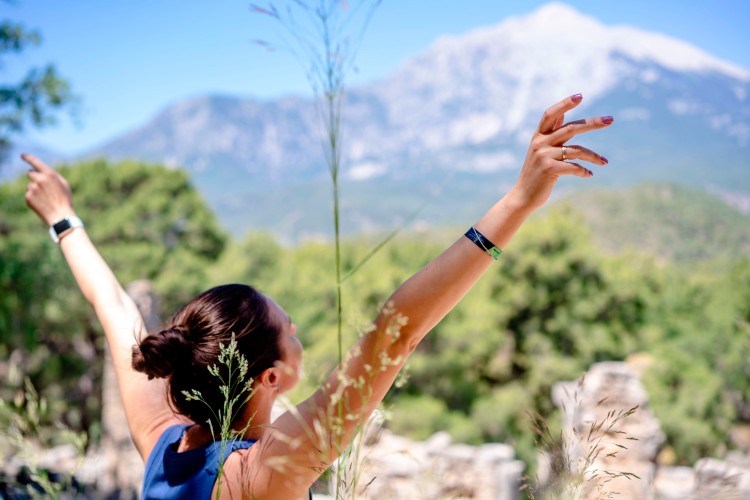 woman-posing-with-raised-arms-on-blurred-nature-background