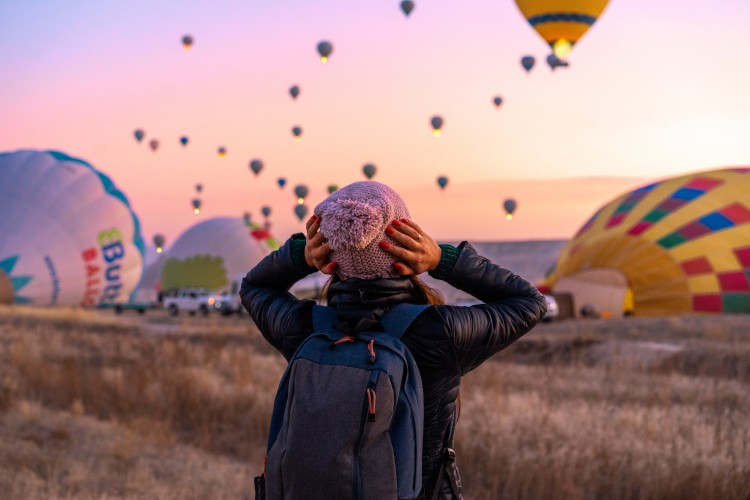 woman-with-backpack-looks-at-balloons-in-cappadocia