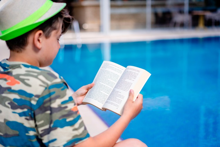 boy-reads-book-at-the-swimming-pool