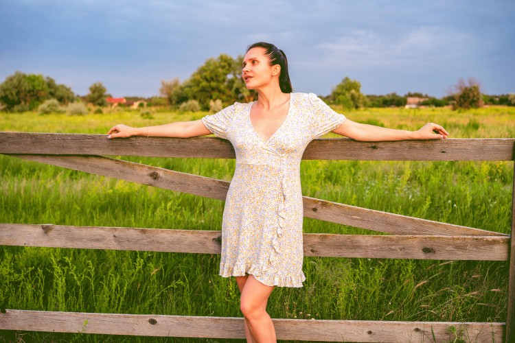 young-woman-in-a-summer-dress-near-a-wooden-fence