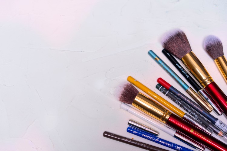 makeup-brushes-with-pencils-on-a-white-wooden-background