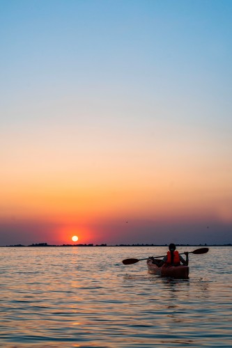 woman-in-kayak-on-a-river-on-the-sunset-background