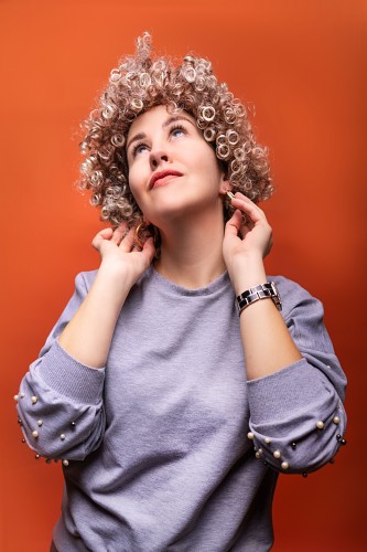 youn-woman-with-curls-on-an-orange-background