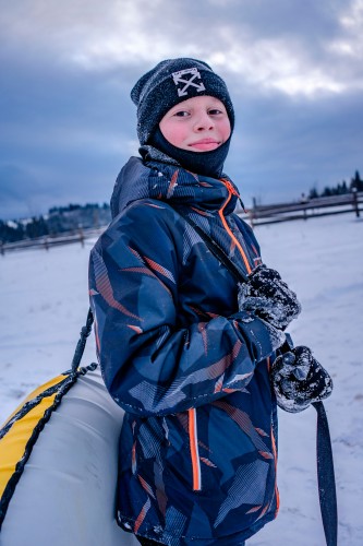 smiling-kid-in-winter-outfit-holding-winter-tube
