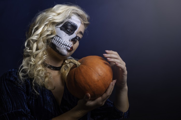 blonde-halloween-girl-with-scary-makeup-holding-pumpkin