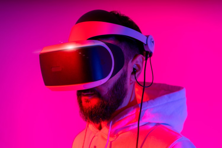 young-man-using-glasses-of-virtual-reality-on-pink-background