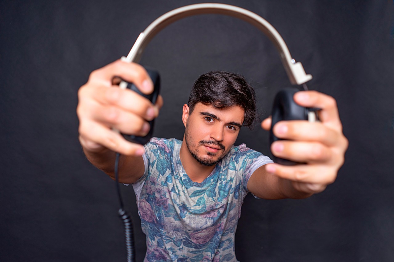 Cheerful brunette man holding headphones