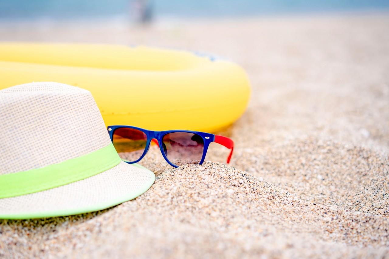 Swim ring, summer hat and sunglasses on the sand