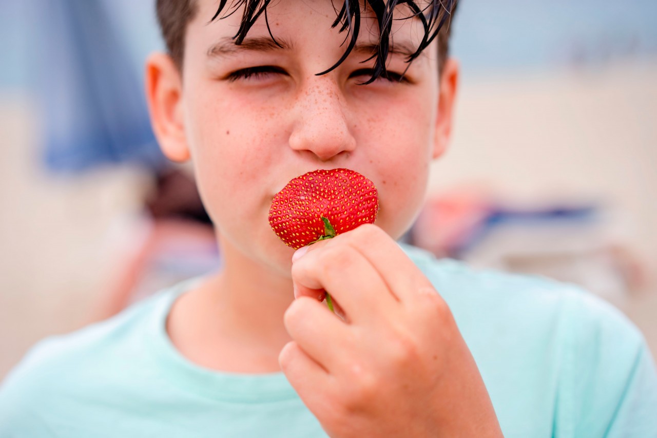 Boy eats strawberry on the blurred background