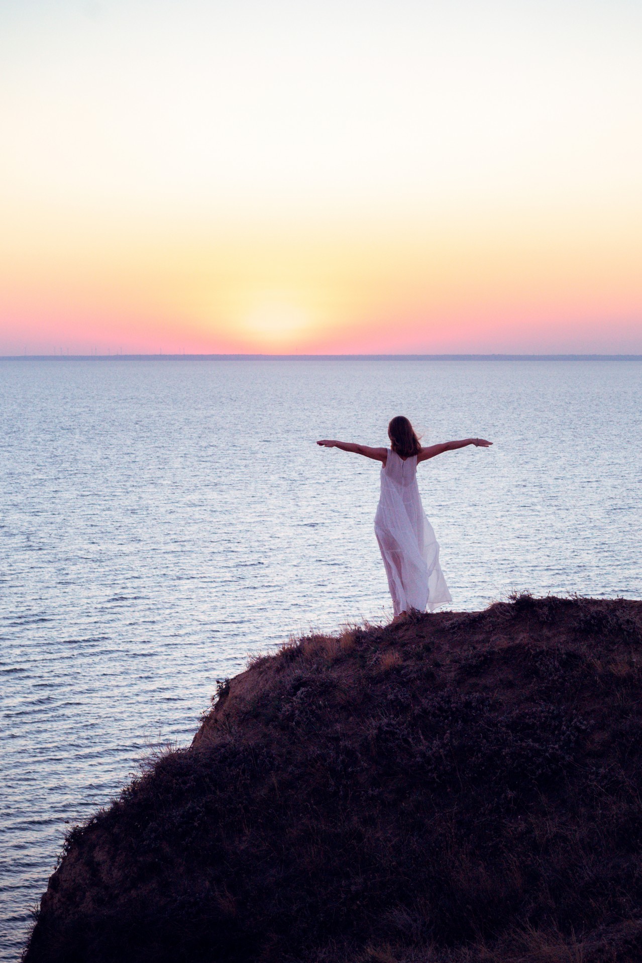 A Young Woman in a White Dress Admires the Sunset