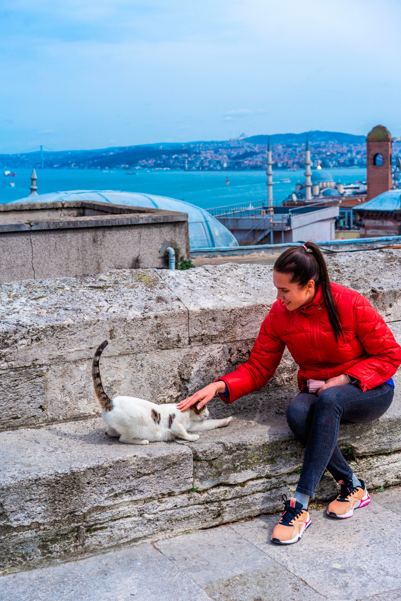 Smiling woman plays with street cat in Istanbul