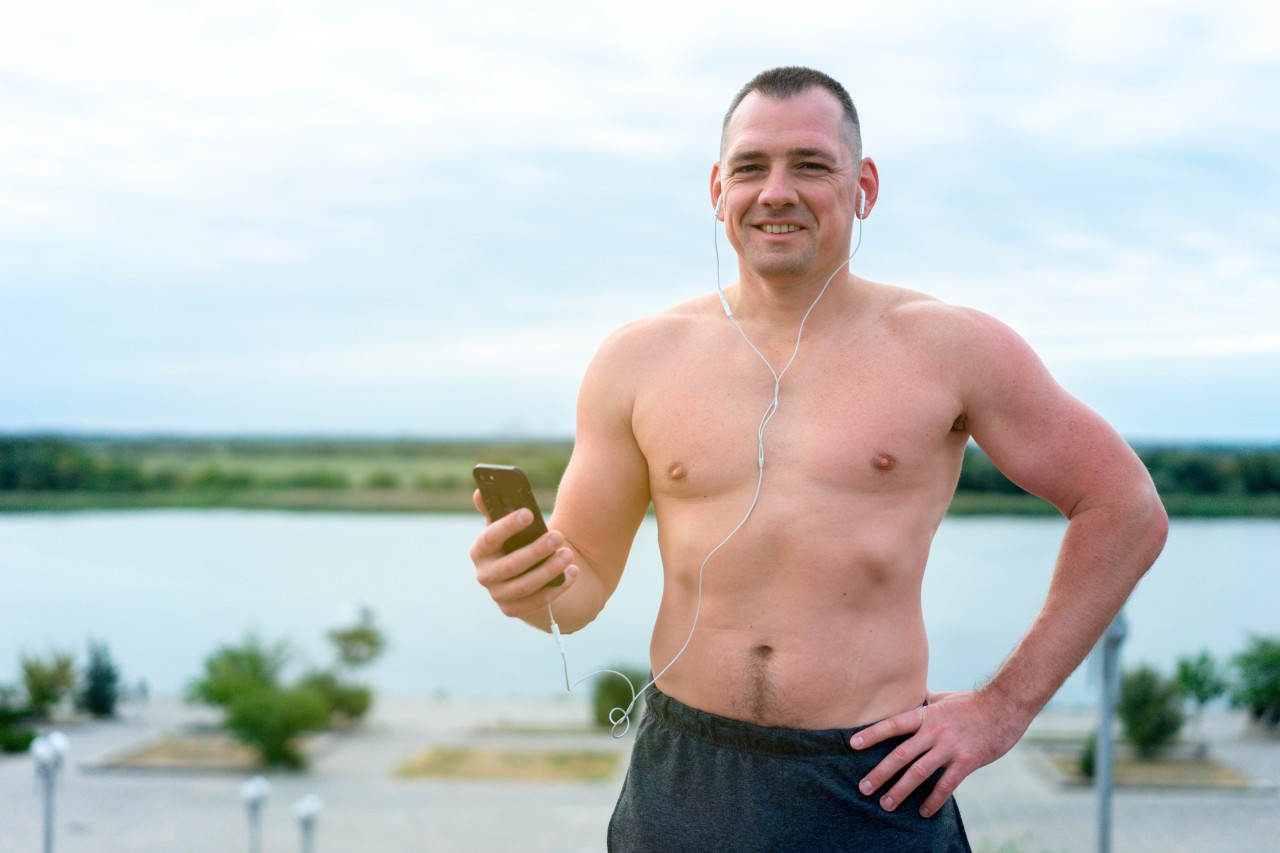Smiling shirtless man listening music during outdoor training