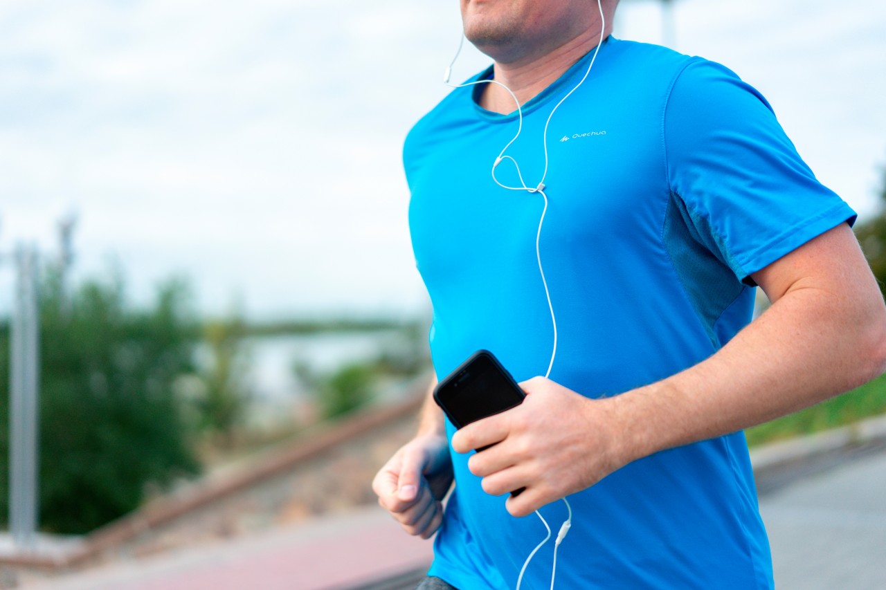 Man in blue t-shirt listening music during sport training