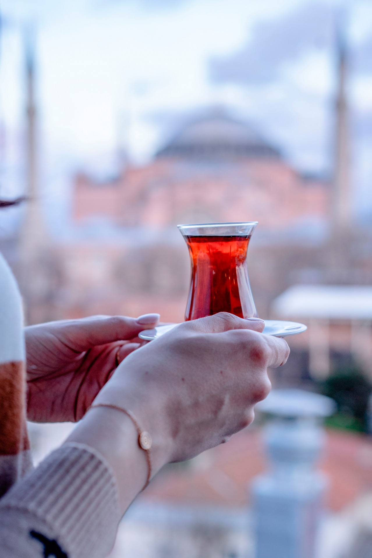 Person holding Turkish tea on blurred background