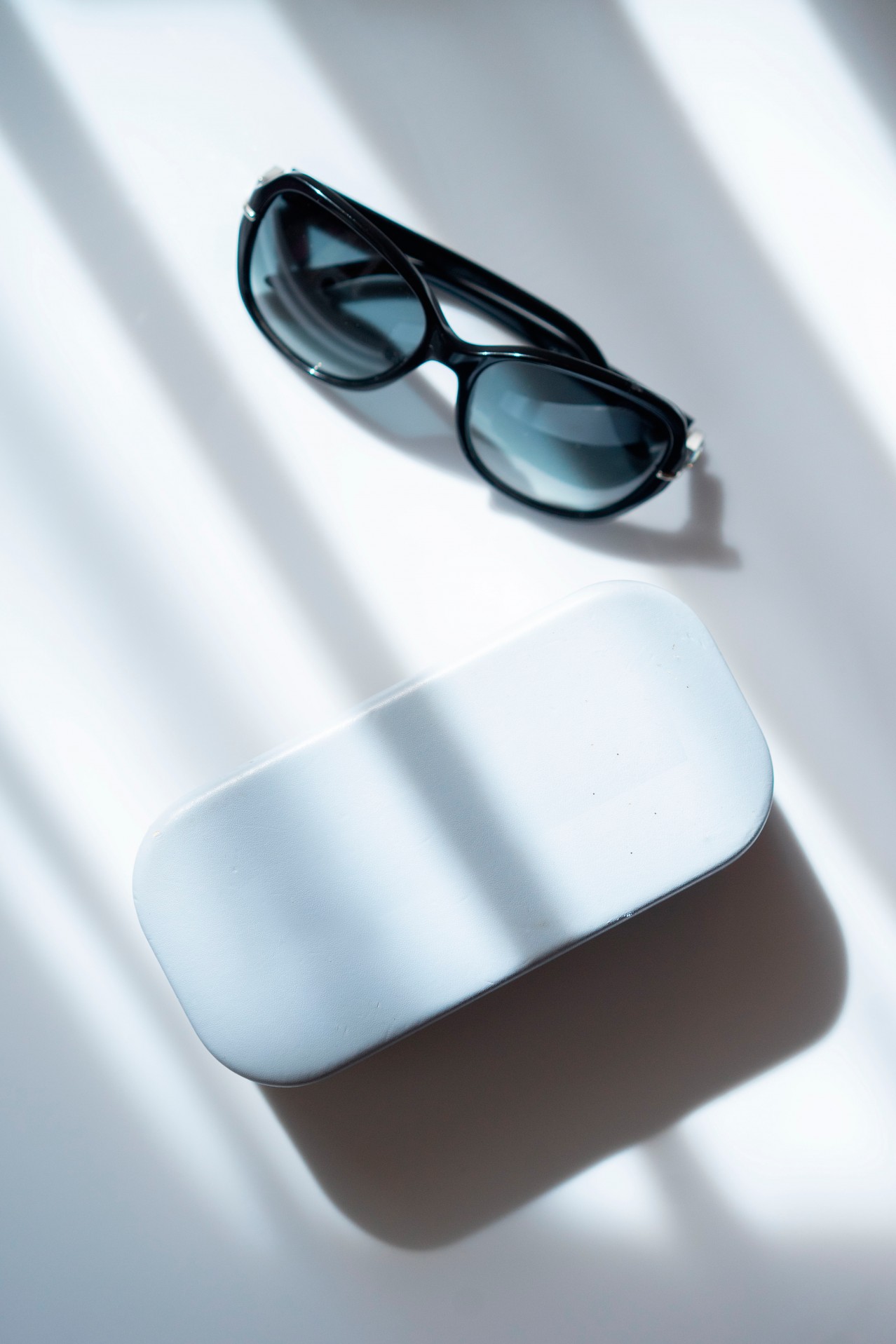 Sunglasses with glasses case under shadows