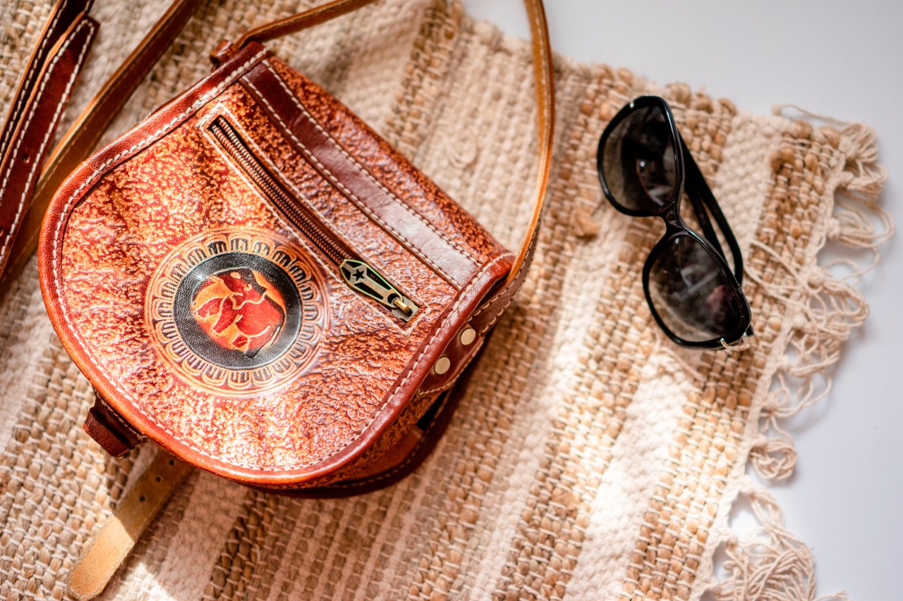 Leather purse and sunglasses on the decorative carpet