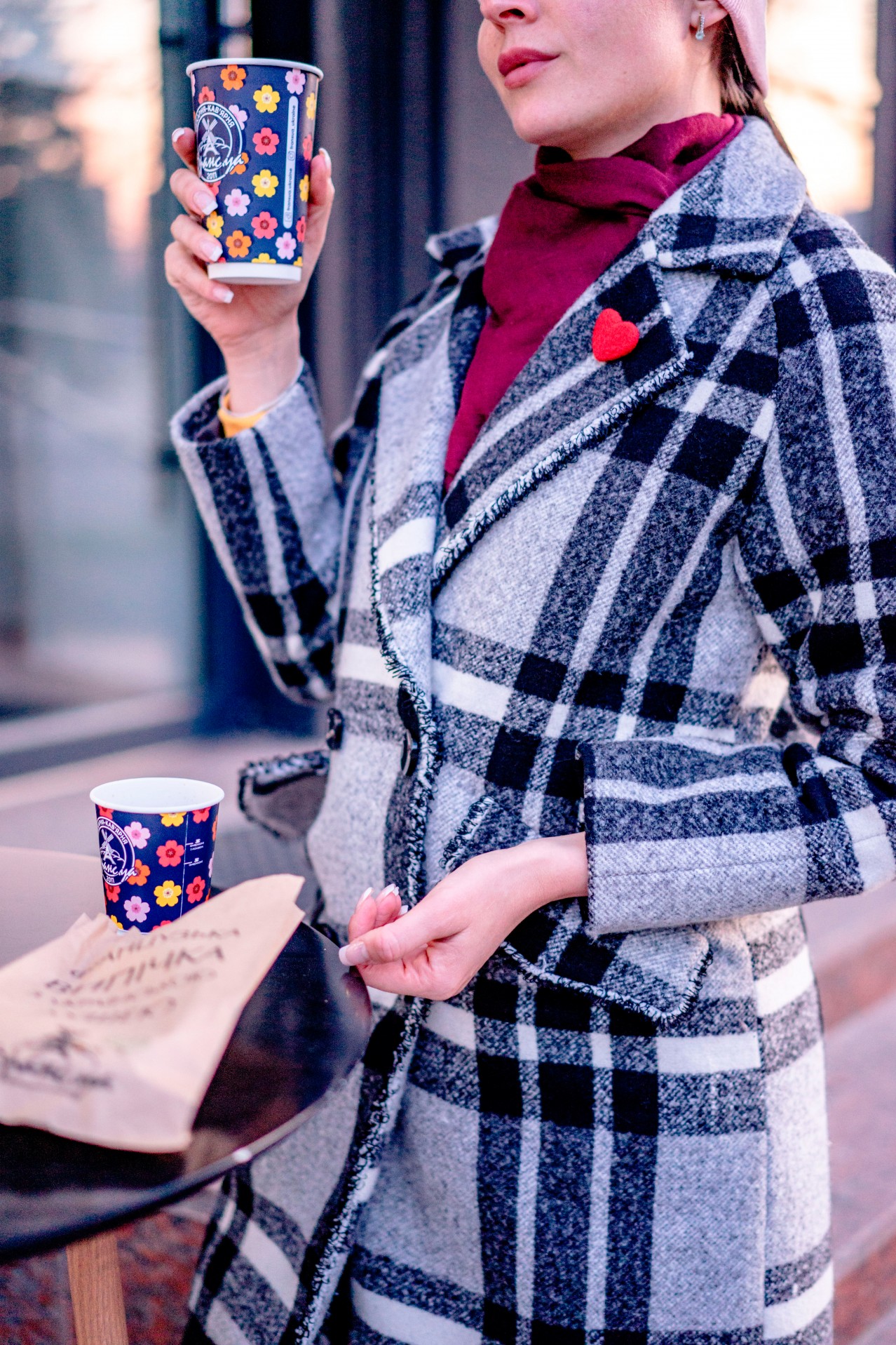 Woman in coat drinking coffee outdoors