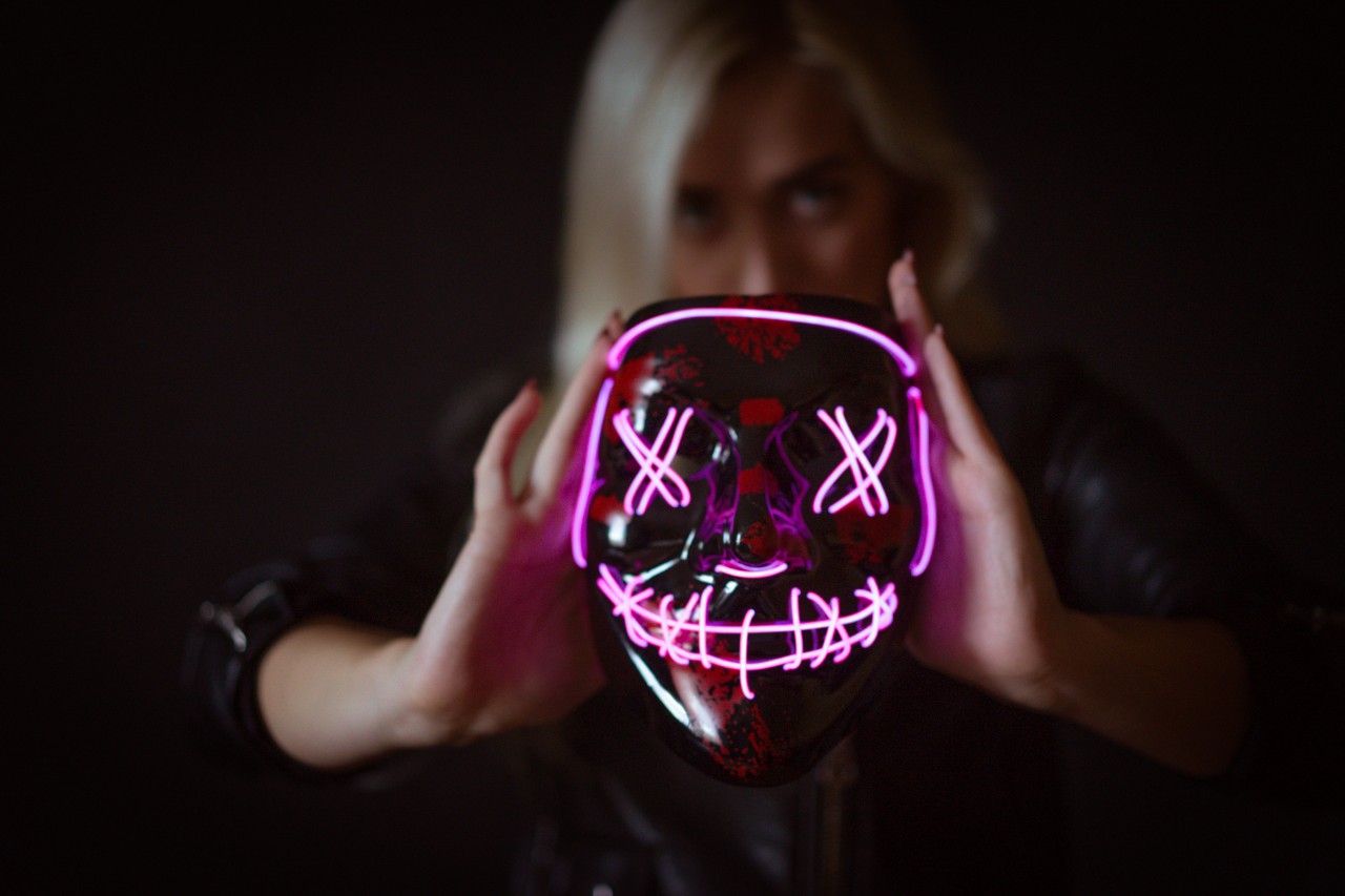 Blonde woman posing on black background with Halloween mask