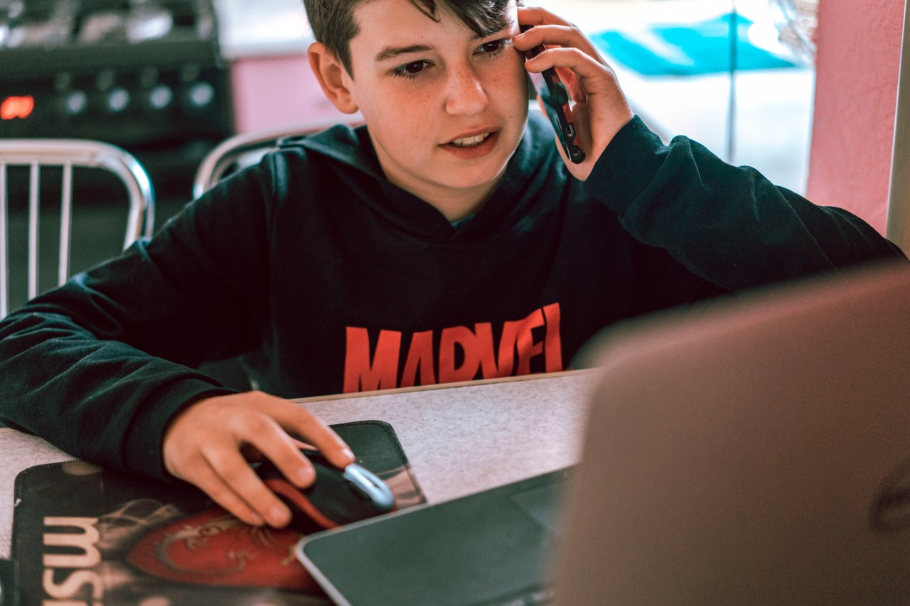 Boy talking on the phone and using laptop