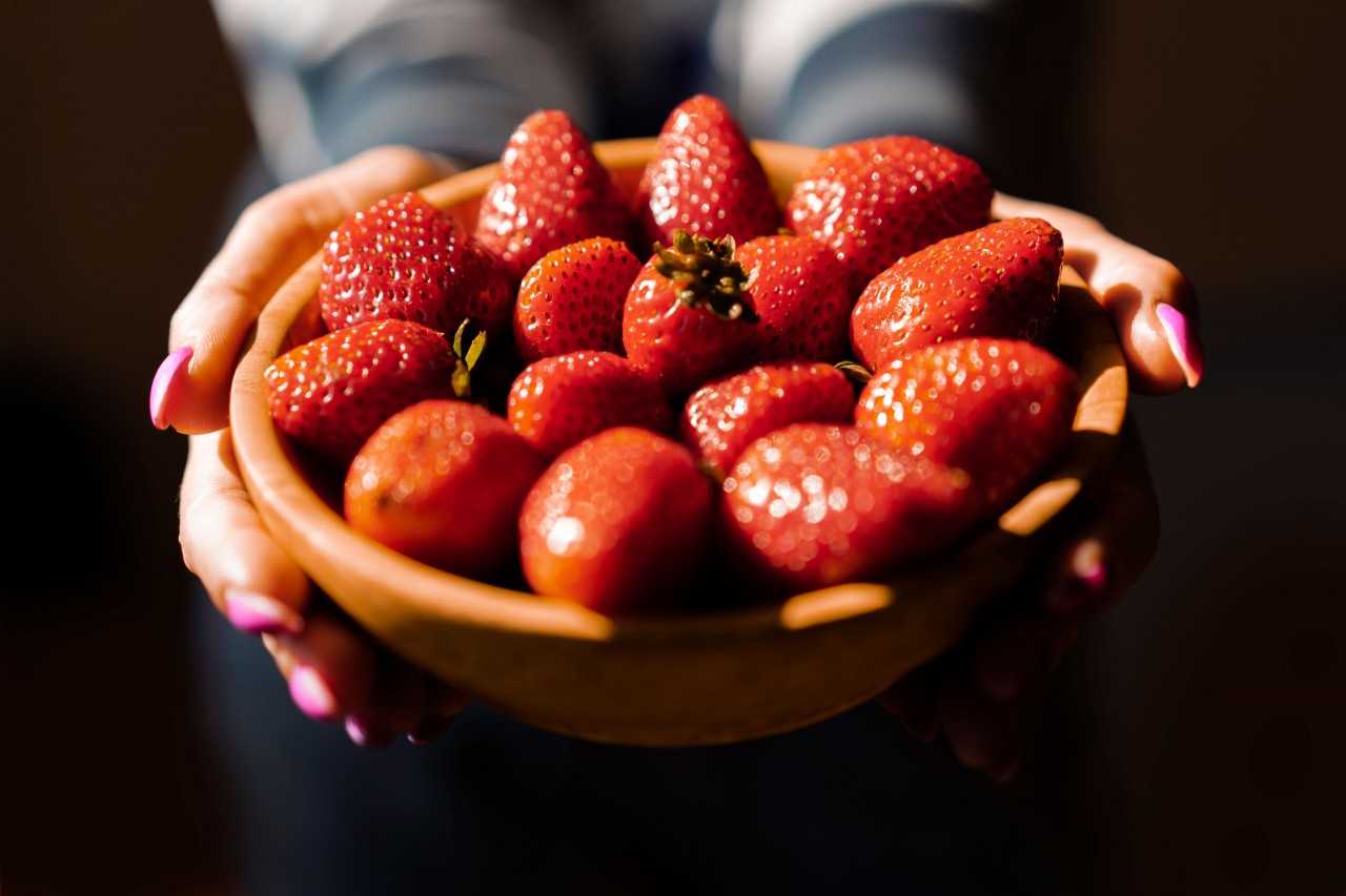 Strawberries in a Wooden Plate in the Hands