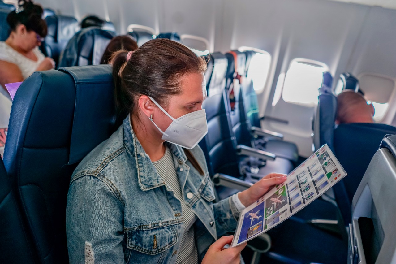 Woman in mask reading information for passengers on the plane