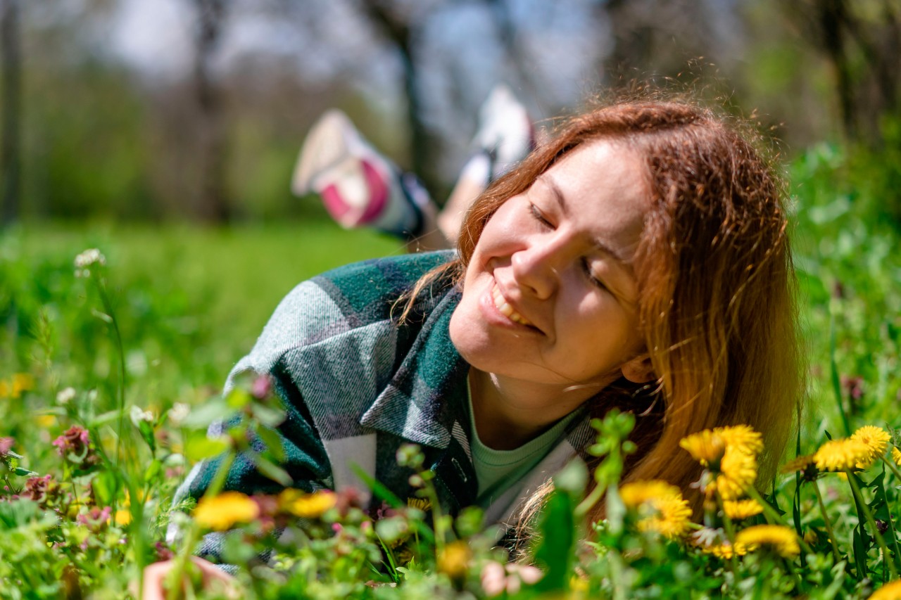Young woman lying on the grass with dandelions