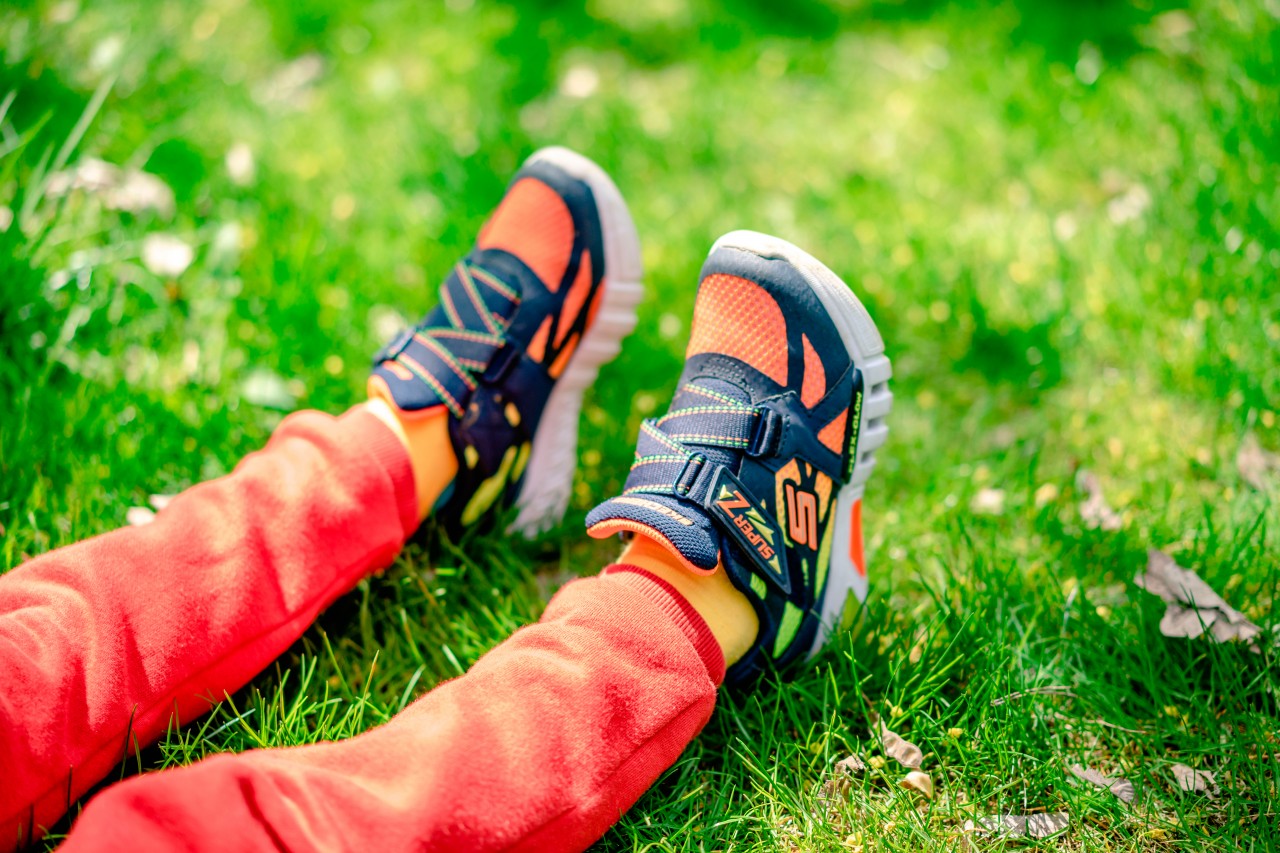 Kids legs in bright sneakers on the grass