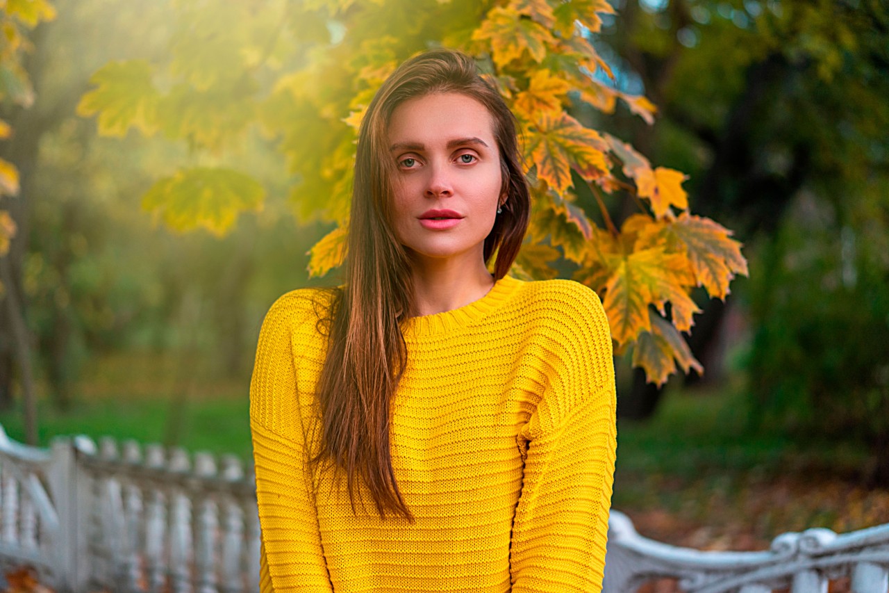 A Young Brunette Woman on a Background of Autumn Trees