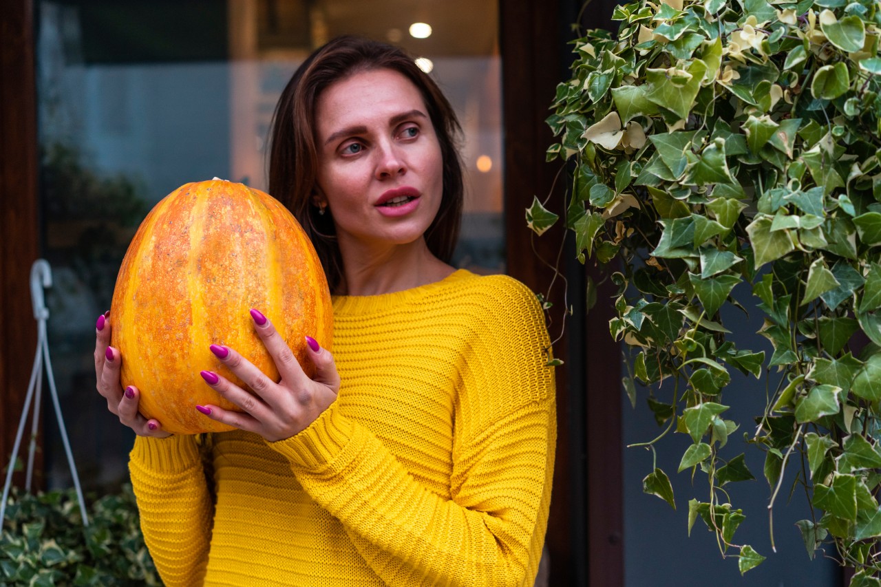 Charming young woman holding pumpkin