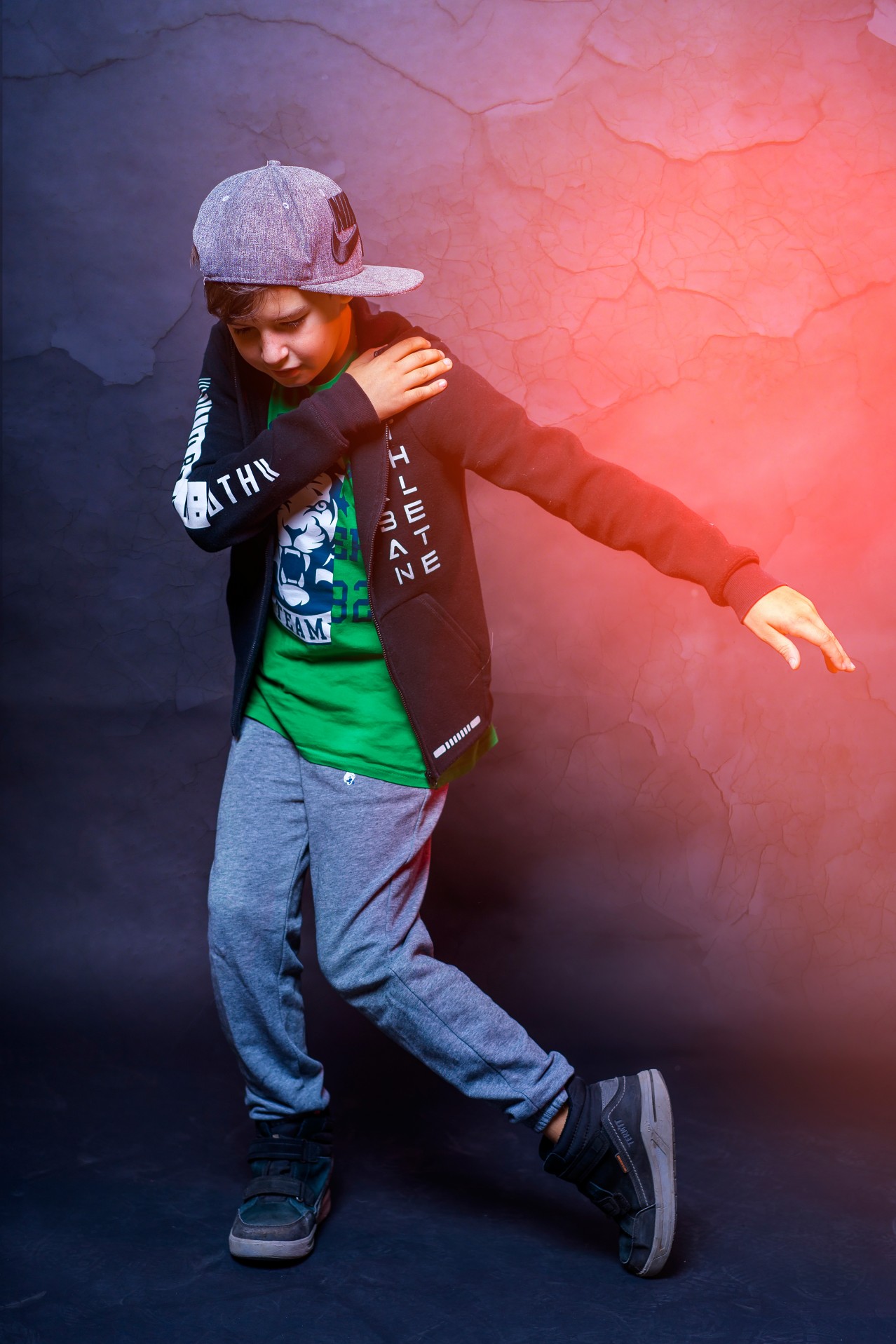 Kid in hip hop hat dancing on dark background