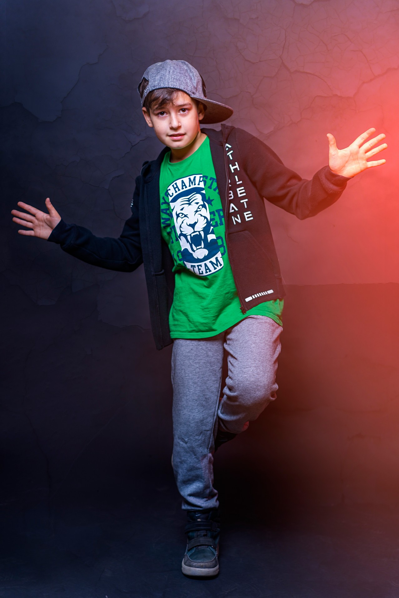 Kid in hip hop outfit posing on dark background