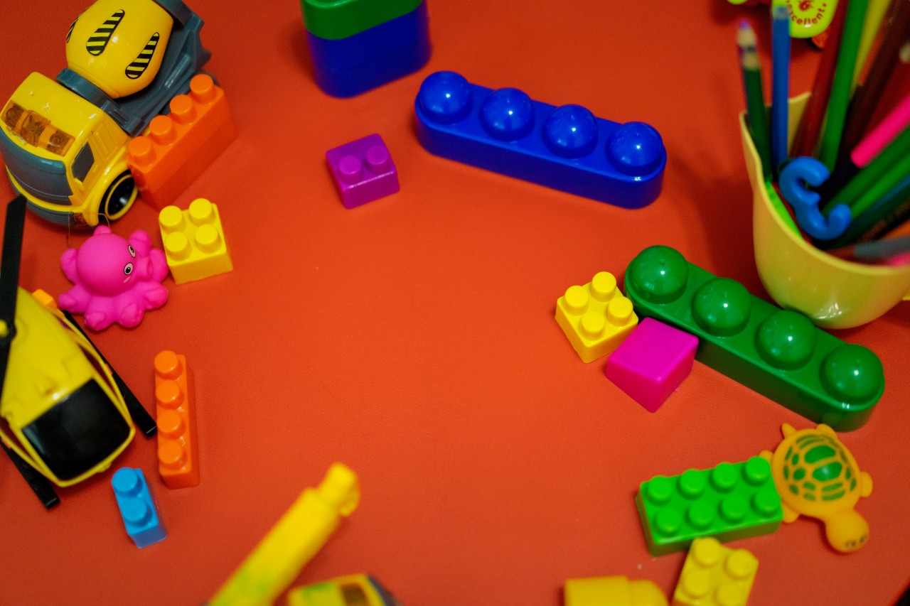 Colorful constructor bricks, pencils and toys on the table
