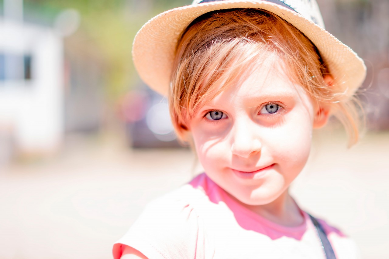 Portrait of a blonde little girl in summer hat