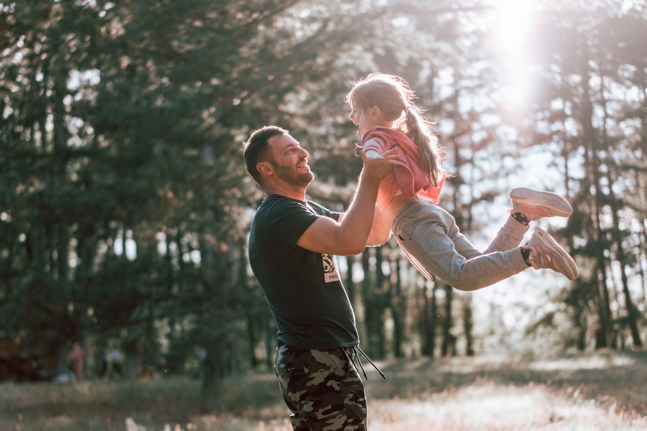 Smiling man plays with daughter in the forest