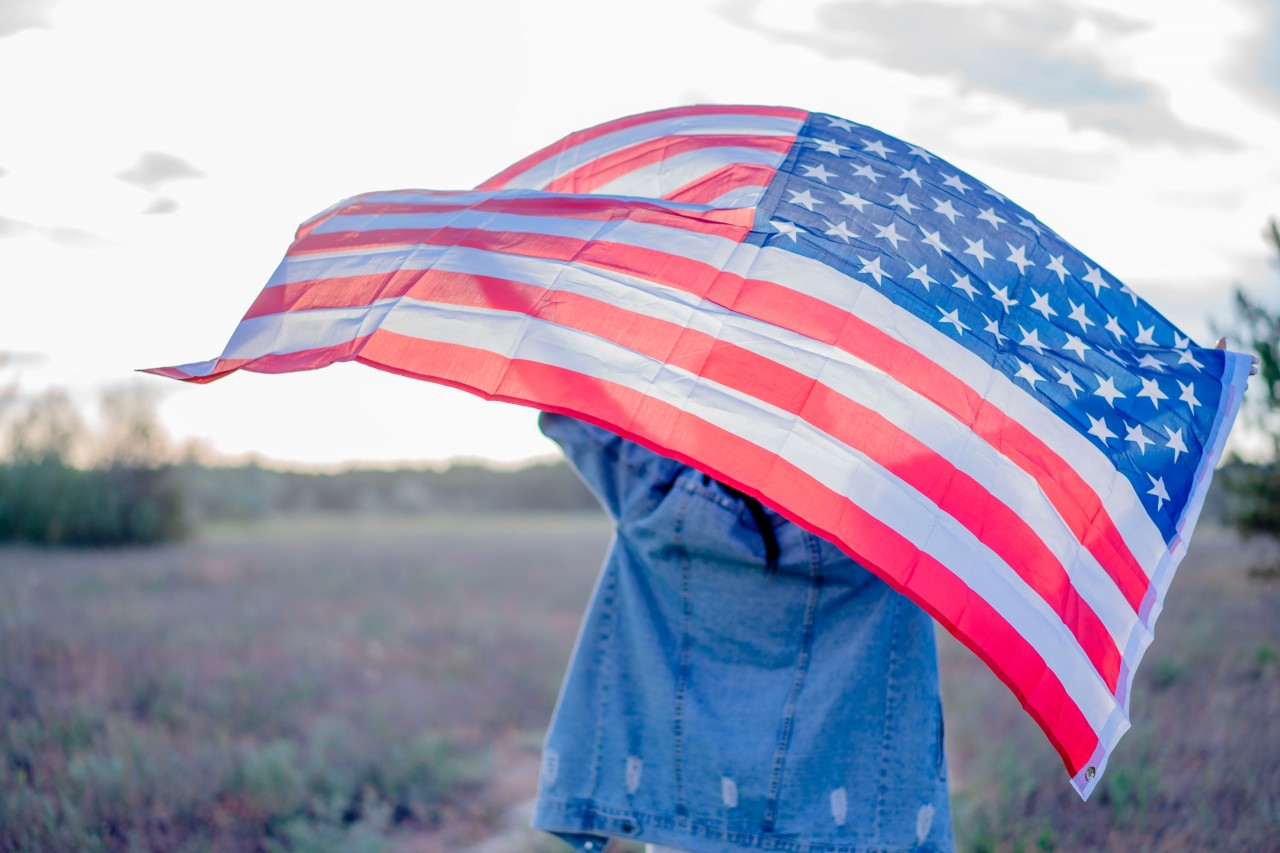 Woman in denim jacket holding American flag