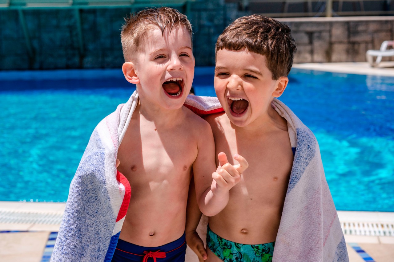 Two boys laughing in front of swimming pool