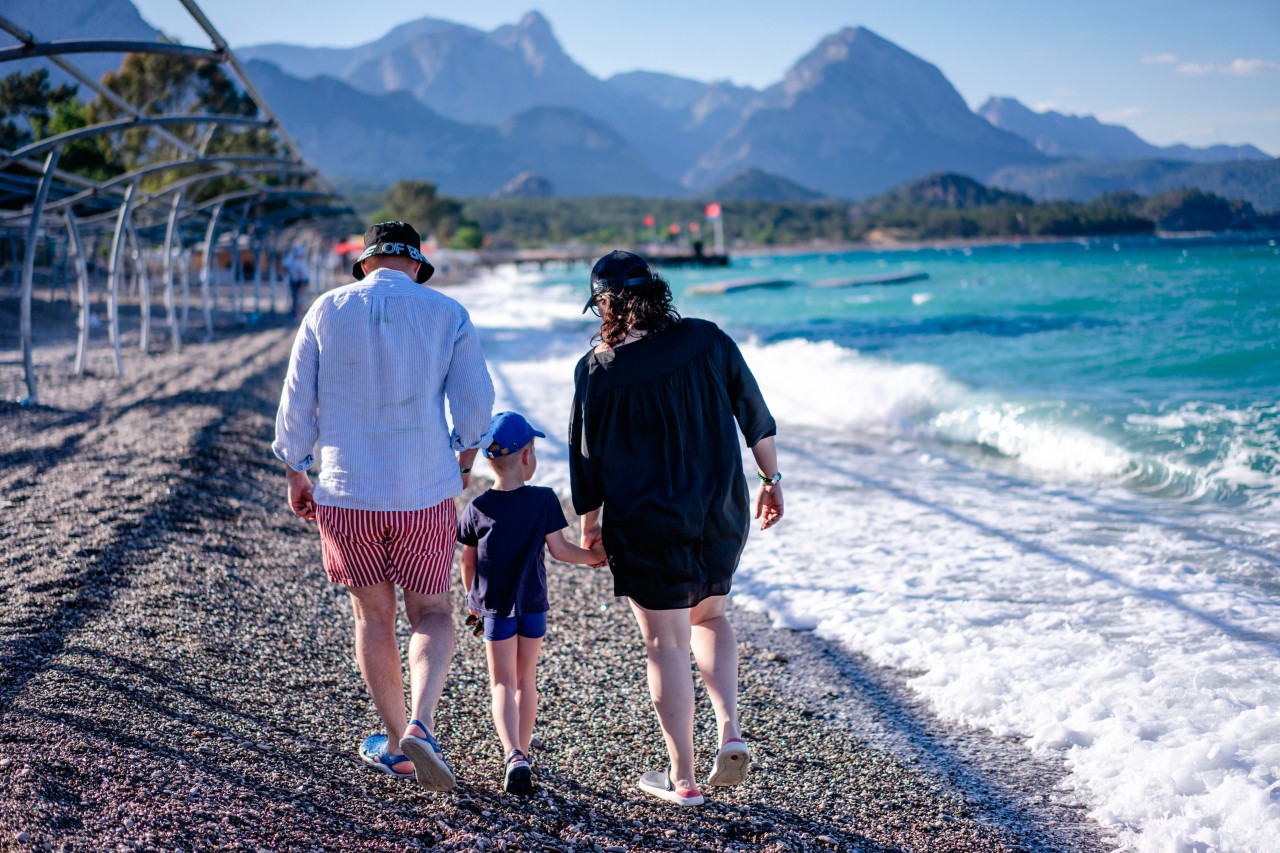 Family walk down the pebble sea beach