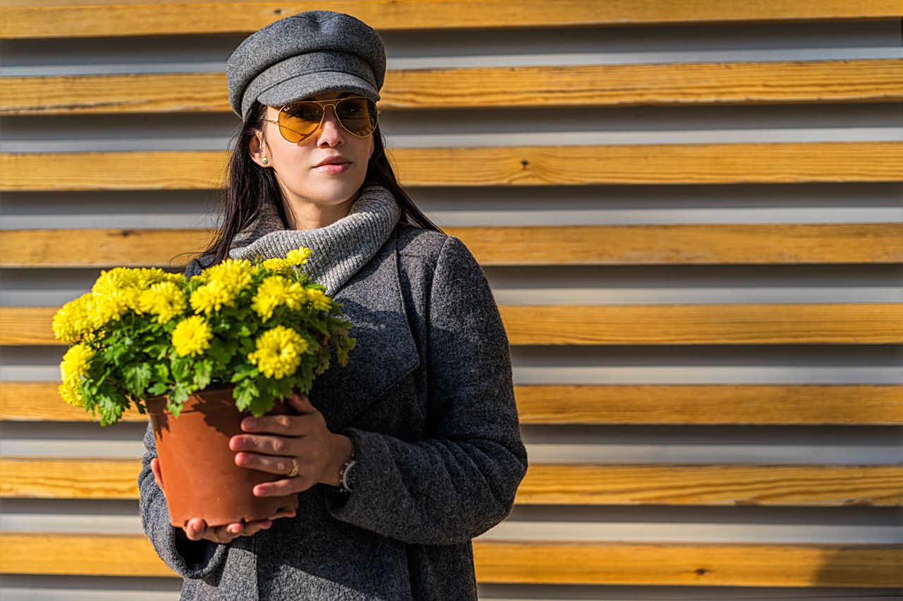 Stylish woman holding yellow flowers