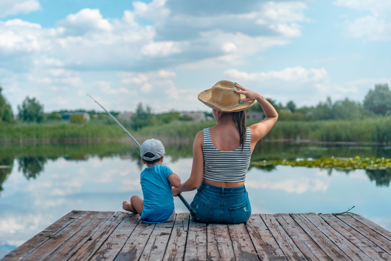 The woman is fishing with her son in summer day