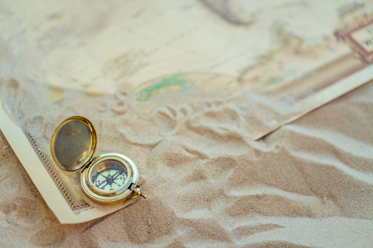 Geographical Map with a Compass on the Yellow Sand