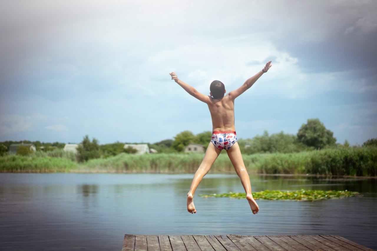 A Boy Jumps into the Water from a Wooden Bridge